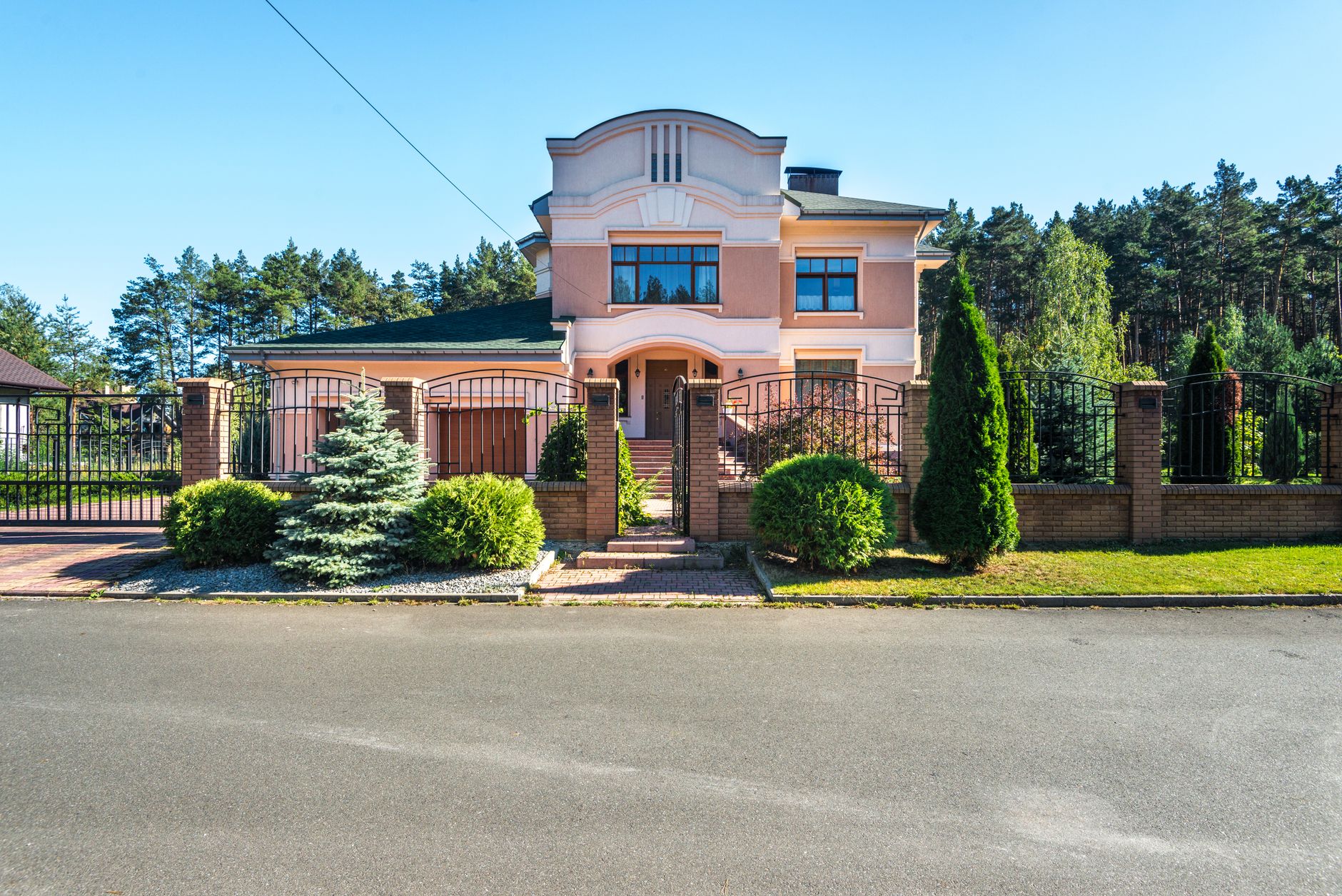Beautiful luxury suburban house with landscaped garden and gated entrance on a sunny day