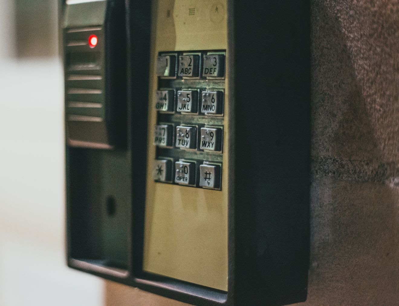 Wall-mounted access keypad with numbered buttons beside a card reader with a red light