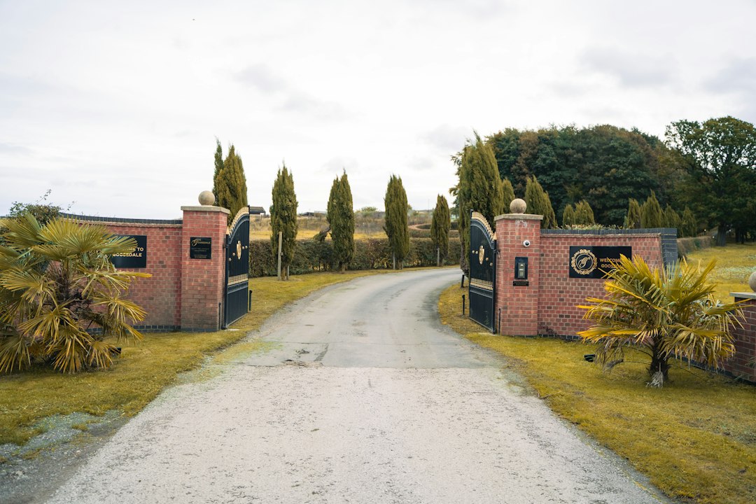 Winding gravel driveway through open brick gates and cypress trees
